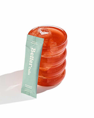 A BetterCalm packet leaning on a glass with red liquid