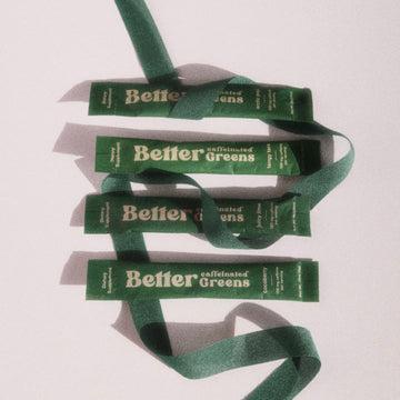 Four green “Better Greens” packets arranged vertically, wrapped with a dark green ribbon on a white background.