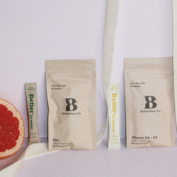 BetterDay Co. supplement packets labeled Zinc and Vitamin D3 + K2 with two stick packs and a sliced grapefruit.