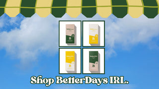 Four product boxes with 'BetterDays' branding against a blue sky with clouds and green and yellow canopy.