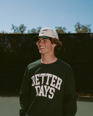 Person wearing a cap and 'Better Days' sweatshirt outdoors